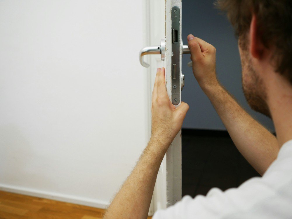 Apprenti serrurier posant une serrure encastrée dans le chant d'une porte pendant un exercice pratique